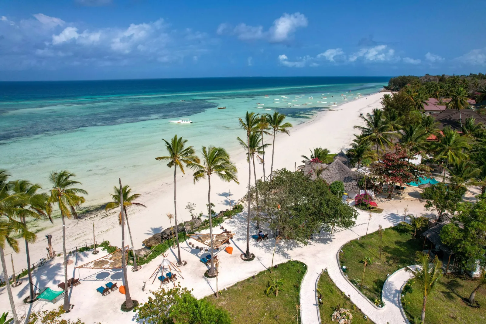 A white sand beach lined with palm trees beside turquoise sea